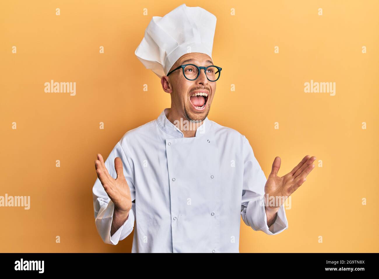 Kahlköpfiger Mann mit Bart in professioneller Koch-Uniform, verrückt und  schreiend mit aggressivem Ausdruck und erhobenen Armen. Frustration Conce  Stockfotografie - Alamy