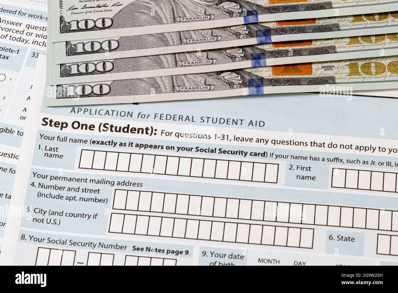 Studentendarlehenantrag und einhundert Dollarscheine. Konzept der College-Studienkredit, Schulden und Schule Sparplan. Stockfoto
