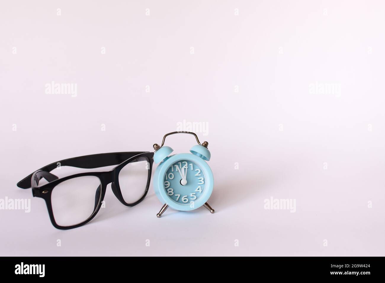 Schwarze Gläser und ein blauer Wecker zeigen 12 zwölf Uhr Stockfoto