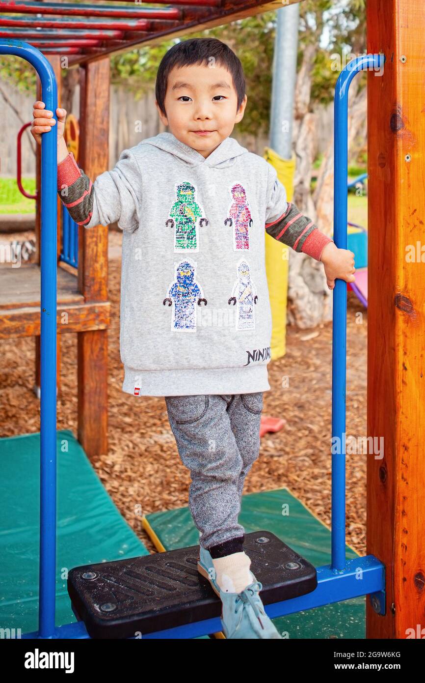 Selbstbewusster Junge, der auf Spielgeräten im Freien steht Stockfoto