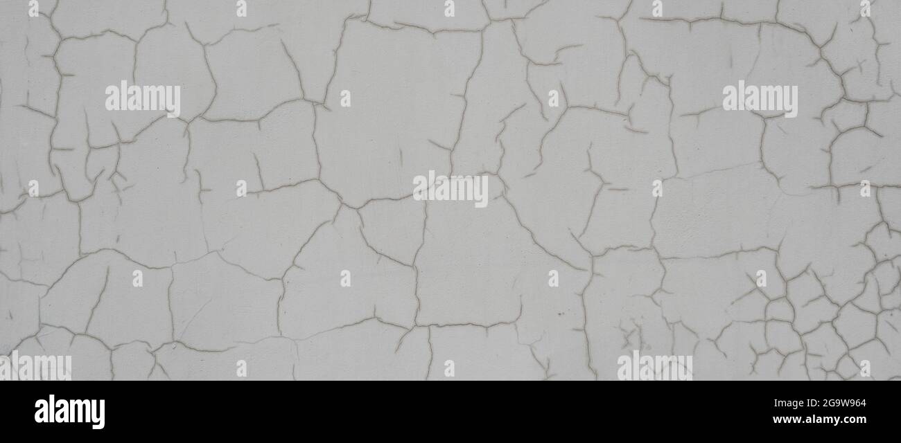 Alte graue Wand mit Rissen. Detailreicher Hintergrund mit schönem abstrakten Muster auf gealterter Zementwand. Stockfoto