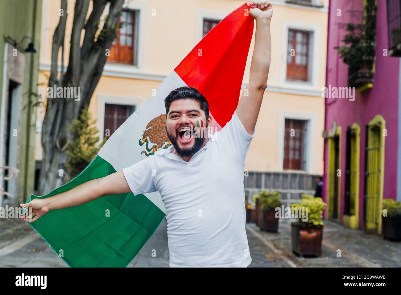 Porträt eines glücklichen Mannes, der in Mexiko-Stadt die mexikanische Flagge schwenkt Stockfoto