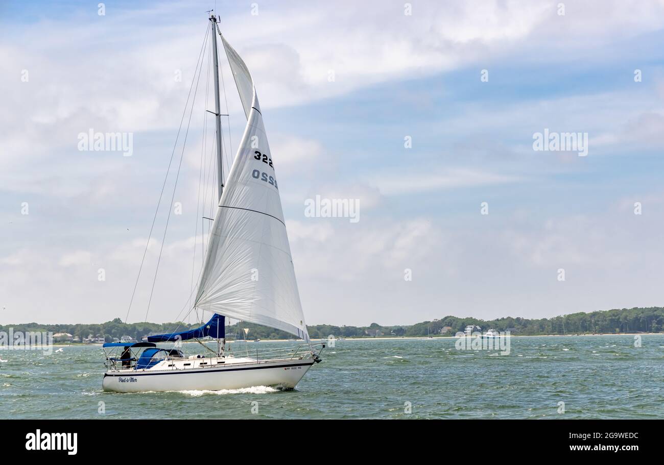 Kleines Segelboot unter Segel, das die Gewässer vor Greenport, NY, durchfährt Stockfoto