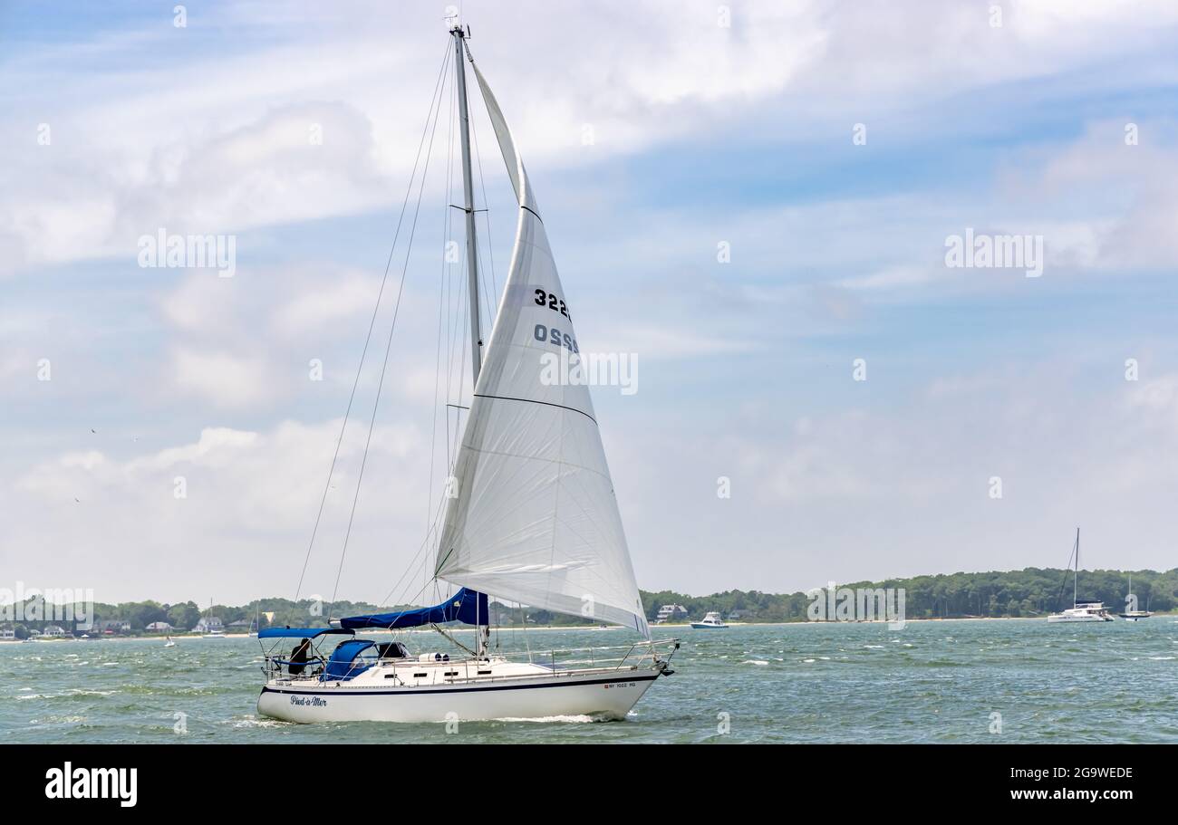 Kleines Segelboot unter Segel, das die Gewässer vor Greenport, NY, durchfährt Stockfoto