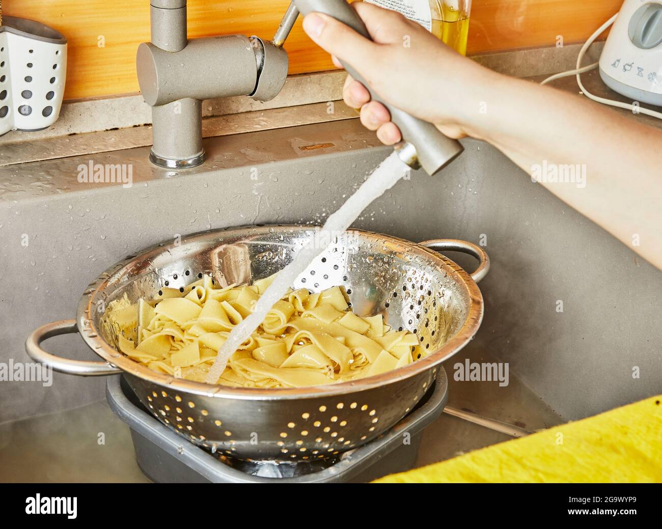 Teenager spült Pasta unter fließendem Wasser für Spaghetti Bolognese nach Rezept aus dem Internet Stockfoto