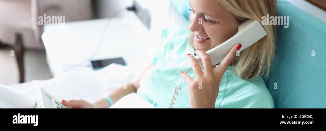 Frau im Bett, die im Hotelzimmer telefoniert Stockfoto