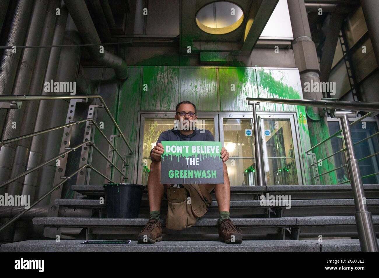 London, England, Großbritannien 28. Juli 2021 Insurance Rebellion wirft grüne Farbe über Lloyds of London, um ihre Greenwashing-Kampagne hervorzuheben. Ein Aktivist wurde verhaftet, nachdem er biologisch abbaubare, wasserbasierte, grüne Farbe über die Vorderseite des Gebäudes geworfen hatte. Der Protestierende, nachdem er die Farbe geworfen hatte, setzte sich hin und wartete auf die Ankunft der Polizei. Ein Sprecher sagte: „Lloyds gibt einfach vor, positive Klimaschutzmaßnahmen zu ergreifen, während es immer noch Teile der fossilen Energiewirtschaft ermöglicht“. Stockfoto
