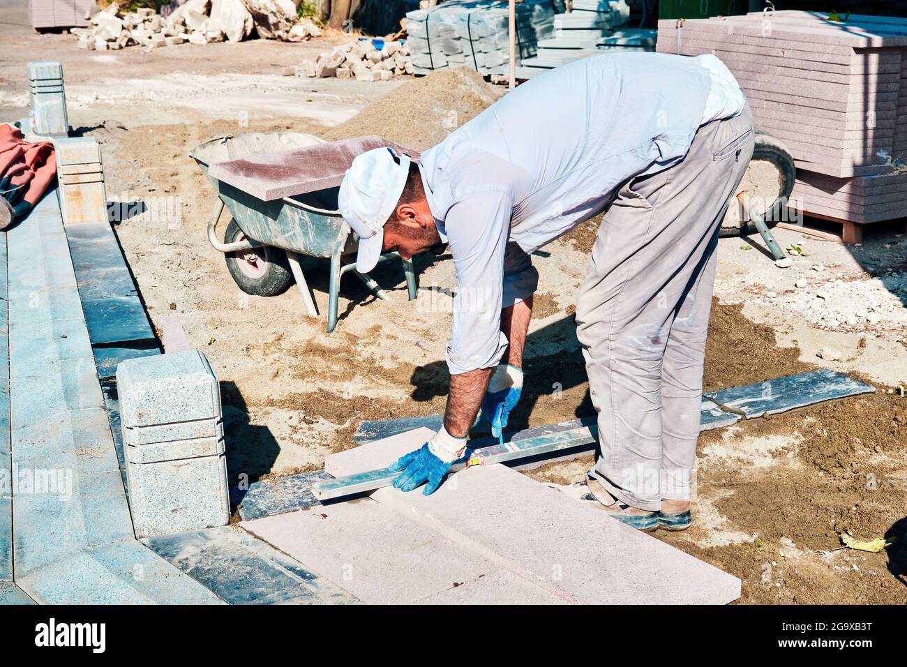 Türkischer Pflaster-Bauarbeiter, der ein Wasserstuhl-Werkzeug zum Auswuchten der Fliesen verwendet. Stockfoto