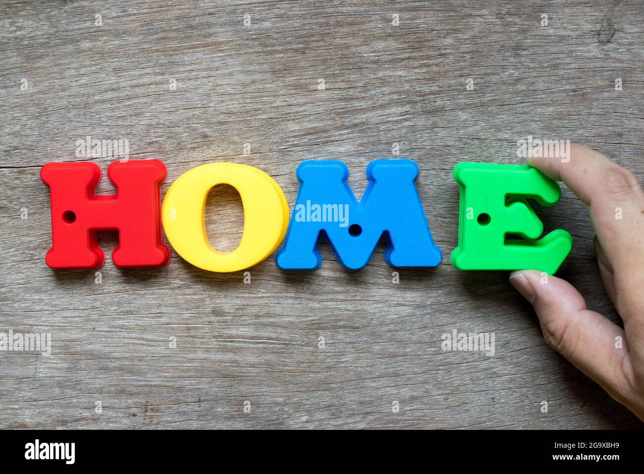 Bunte Kunststoff-Alphabet in Wort zu Hause mit Hand halten E auf Holz Hintergrund zu erfüllen (Konzept des Traumhauses, glückliche Familie, Hypothek Darlehen, Eigentum ow Stockfoto