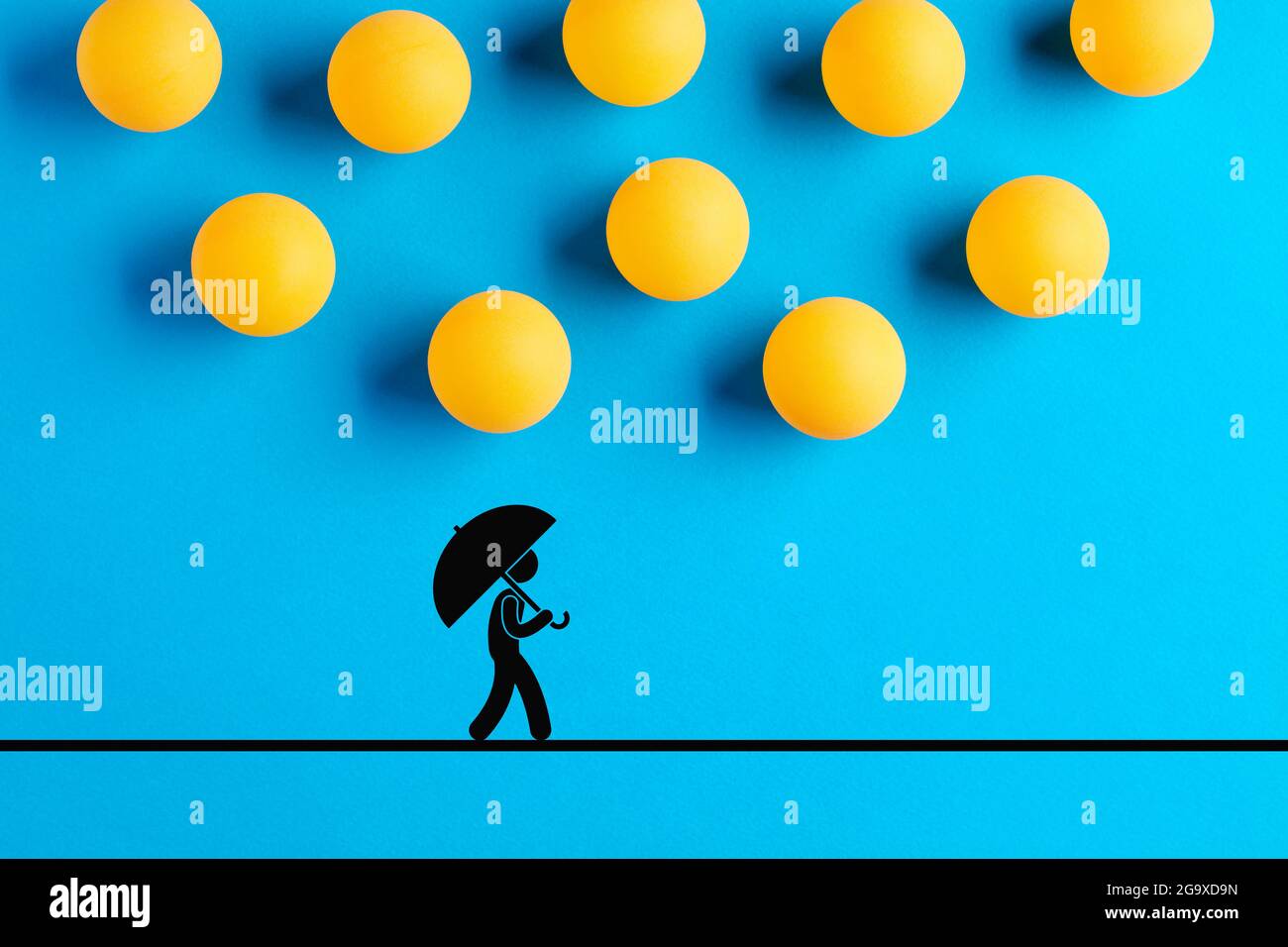 Tischtennisbälle, die als Regentropfen entworfen wurden, fallen auf die Ikone eines Mannes, der mit einem Regenschirm läuft. Katastrophe, Unglück, Unfall, Risiko oder Gefahr überkommen Stockfoto