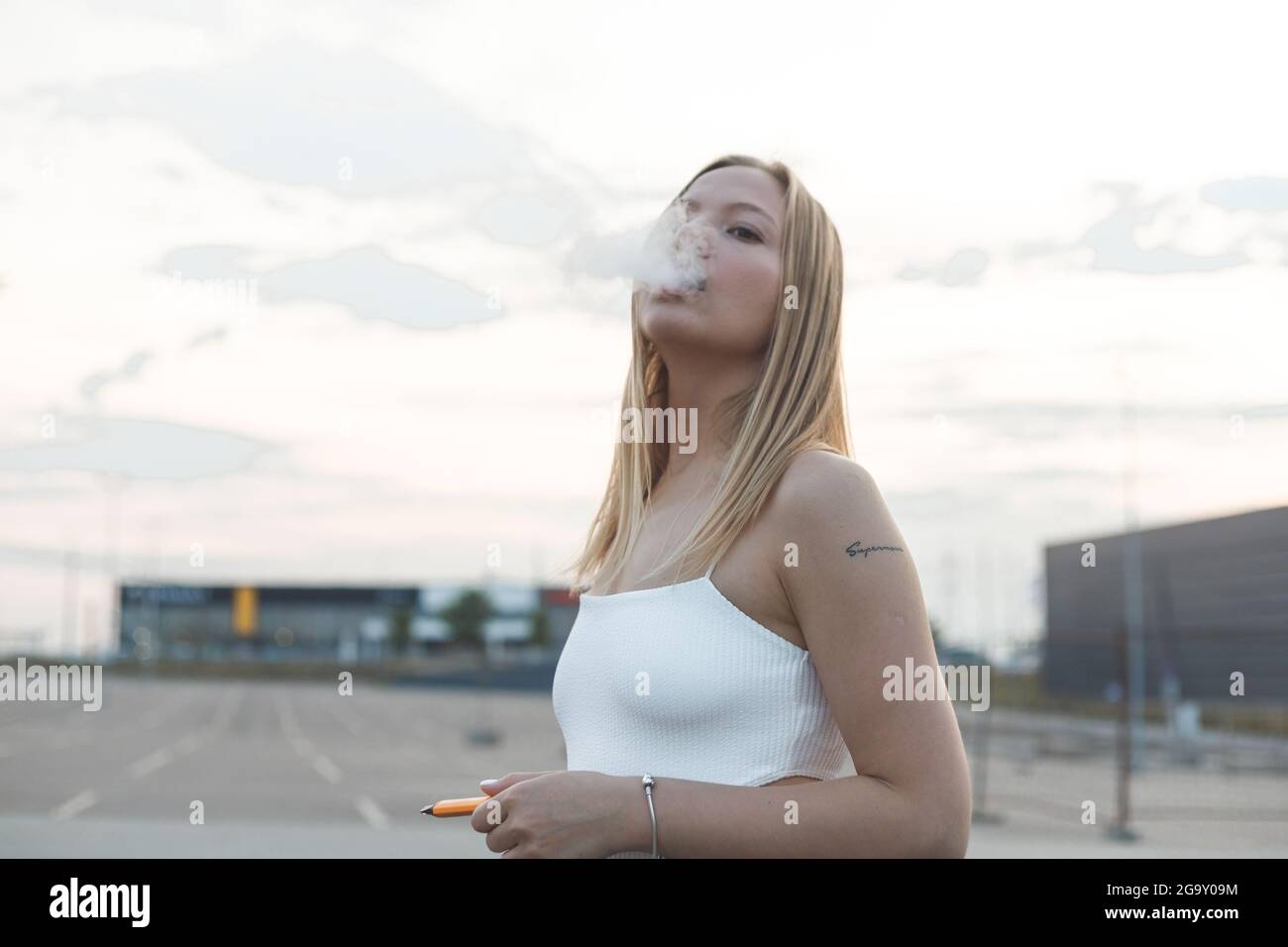 Blonde Frau in der Stadt mit elektronischer Zigarre Vaping Stockfoto