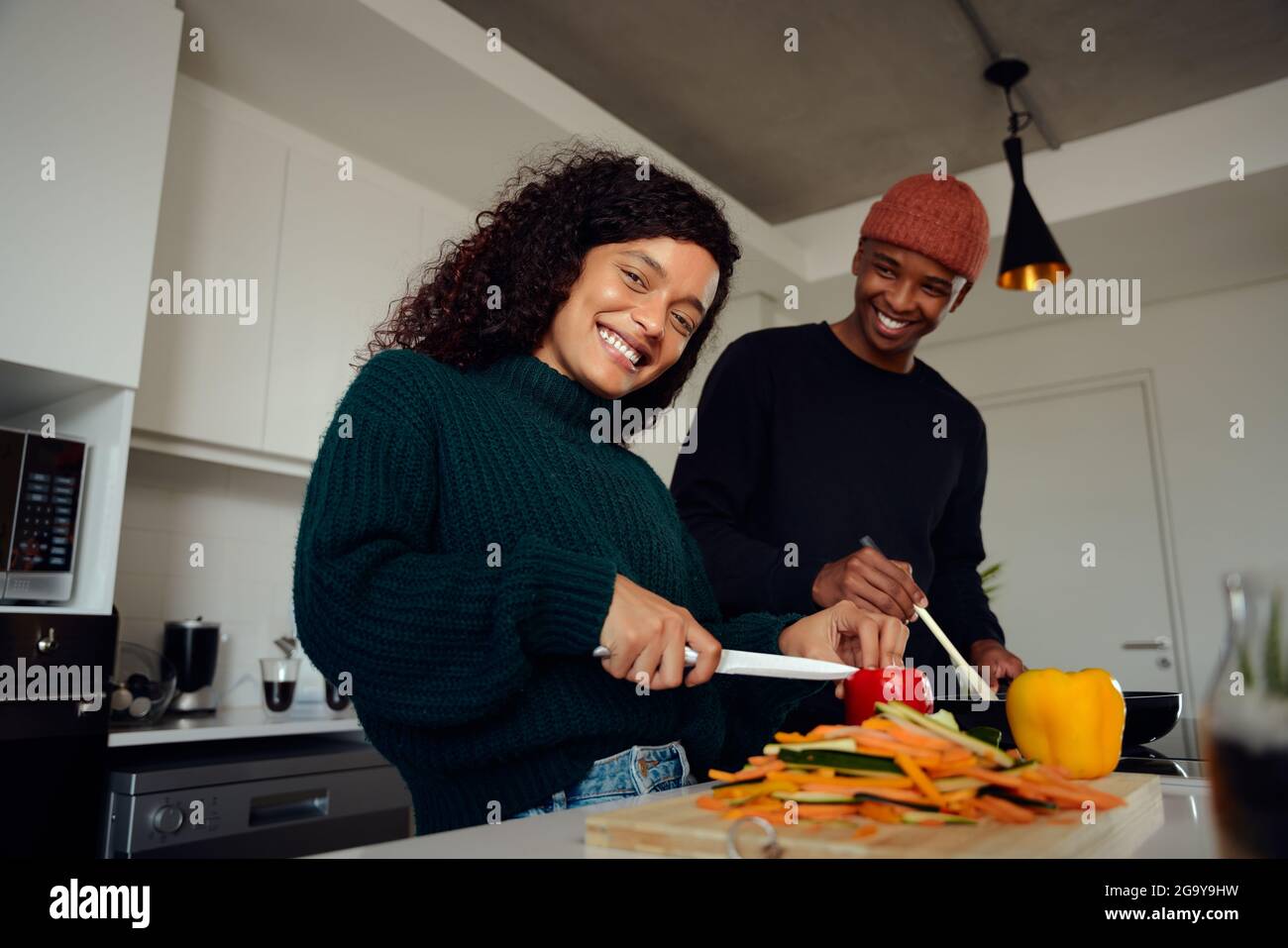 Junges gemischtes Rennpaar, das in der Küche zu Hause kocht. Glückliches Paar, das Essen zubereitete und lächelte. Hochwertige Fotos Stockfoto