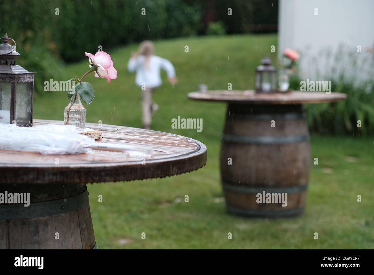 Rückansicht eines Mädchens in einem Garten, das aus dem Regen auf ein Haus in Frankreich zuläuft Stockfoto