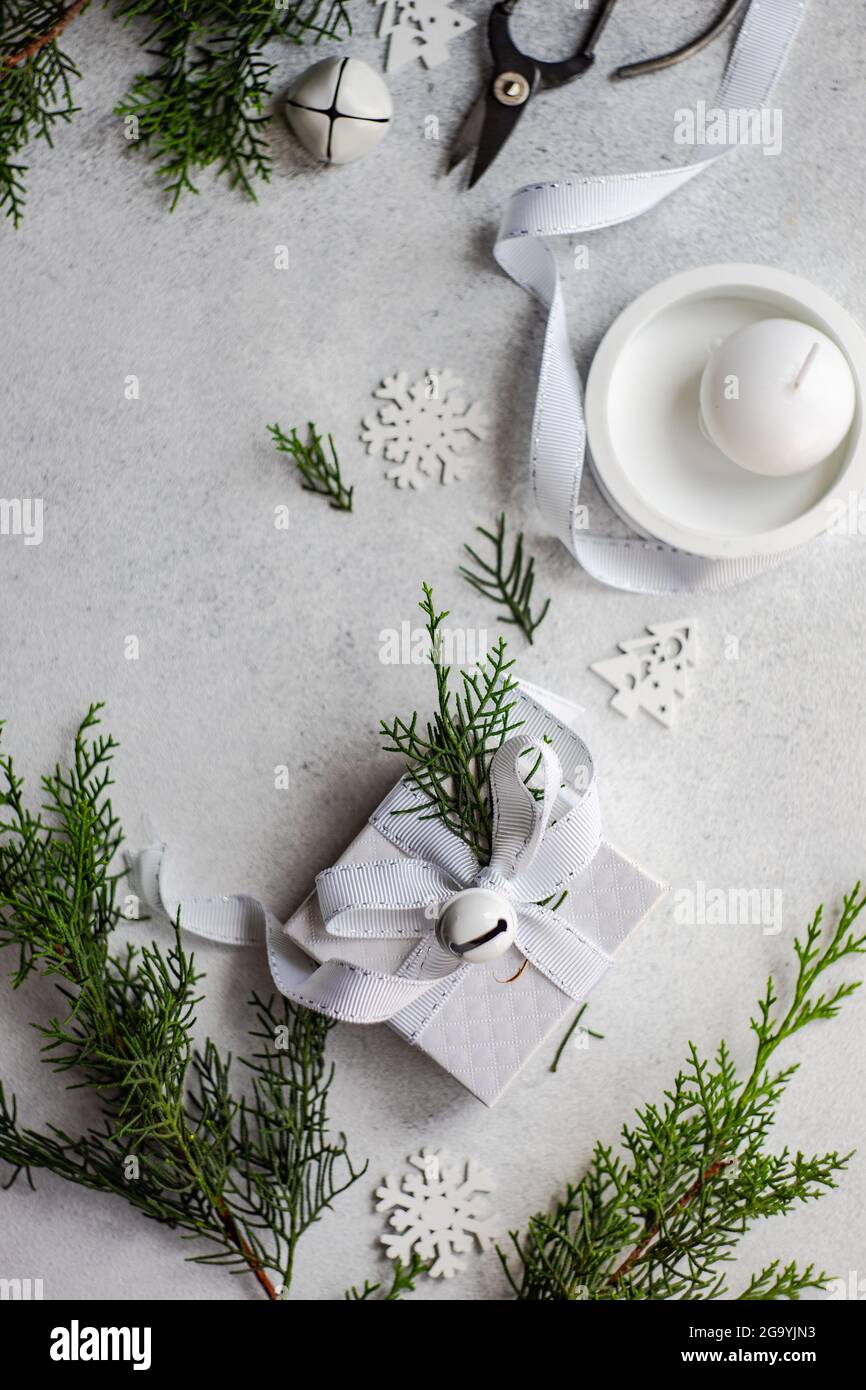 Ansicht eines eingewickelten weihnachtsgeschenks mit rustikaler Thuja-Laub-Dekoration neben einer Kerze Stockfoto