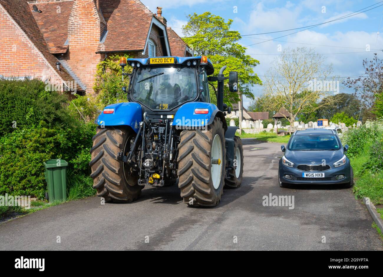 Rückansicht eines großen landwirtschaftlichen Traktors mit großen Hinterreifen in einer engen Wohnstraße in England, Großbritannien. Stockfoto