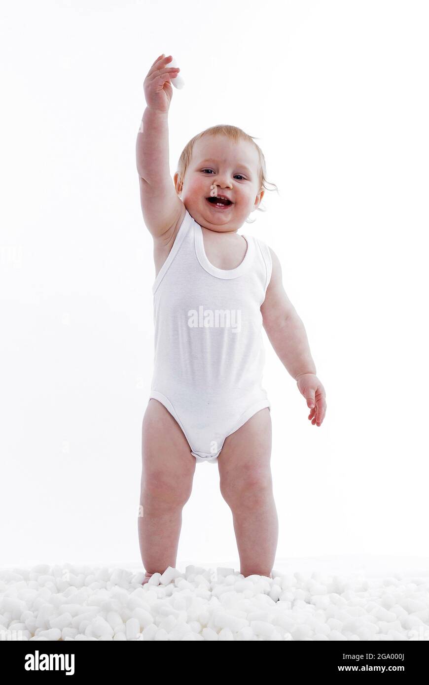 Glückliches Kleinkind im Babybody, das in den Verpackungsflocken steht Stockfoto