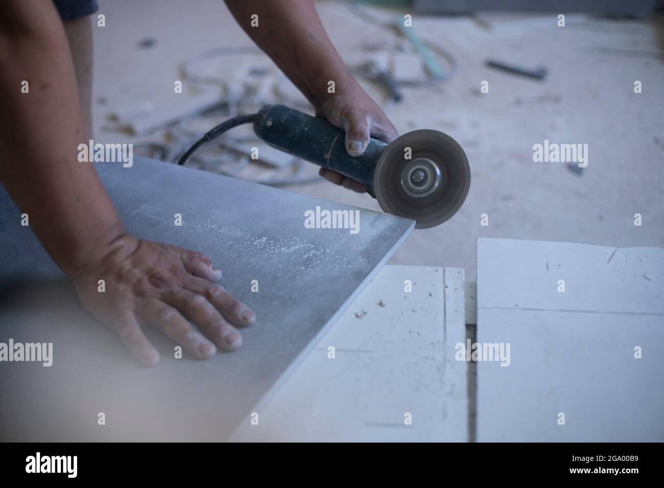 Hände eines lateinischen Arbeiters, der mit einem elektrischen Schleifer schneidet Stockfoto