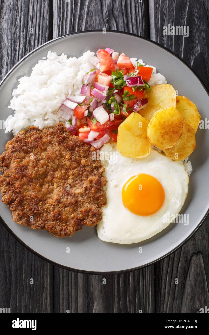 Silpancho ist eine unglaubliche bolivianische Mahlzeit aus Reis und wird mit einem in der Pfanne gebratenen Burger, Salsa, gebratenen Kartoffeln und Ei in der Nähe auf dem Teller serviert Stockfoto