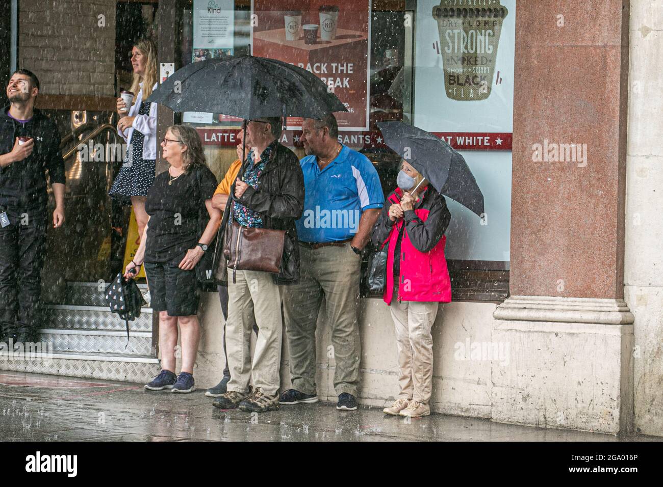 WESTMINSTER LONDON 28 Juli 2021 . Fußgänger drängten sich während eines sintflutartigen Regenguts in Whitehall London mit Regenschirmen zusammen, während Wetterprognosen einen unruhigen Tag vorhersagen, der von Regen und Sonneneinflüssen durchsetzt ist. Credit amer Ghazzal/Alamy Live News Stockfoto