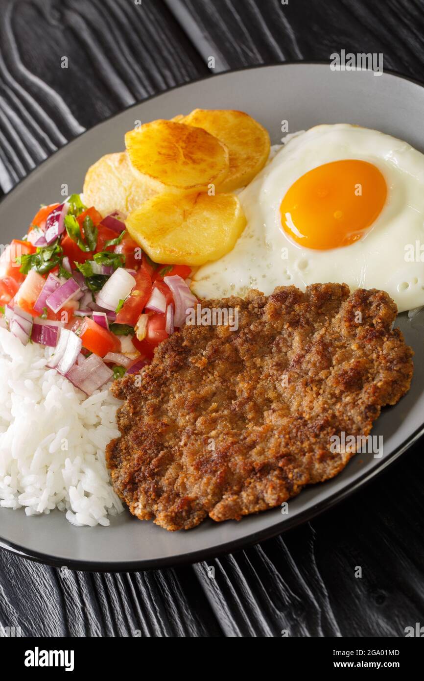 Silpancho ist eine unglaubliche bolivianische Mahlzeit aus Reis und wird mit einem in der Pfanne gebratenen Burger, Salsa, gebratenen Kartoffeln und Ei in der Nähe auf dem Teller serviert Stockfoto