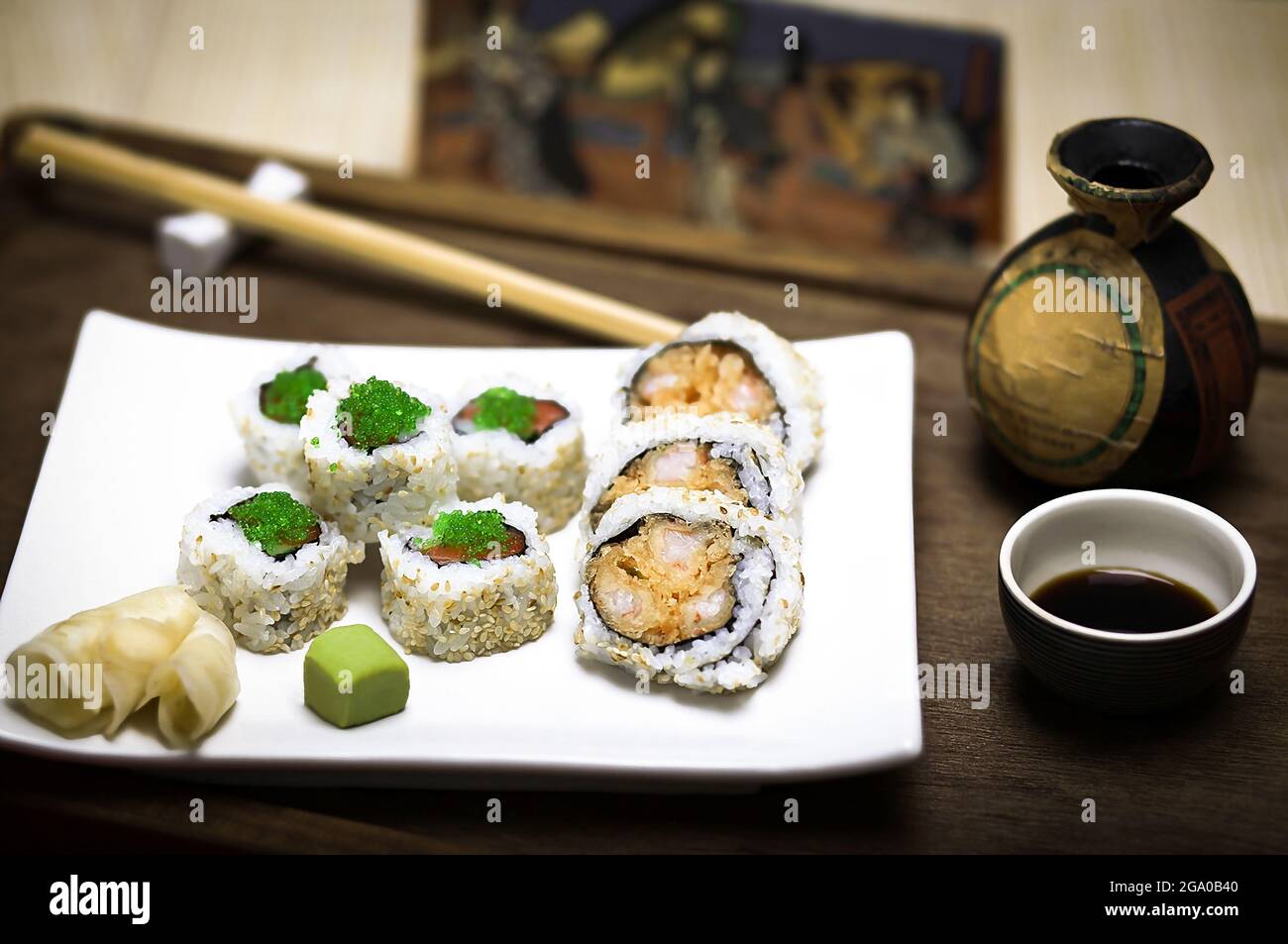 Ein eleganter weißer Teller mit frischem, gesundem Gourmet-Maki-Sushi in Scheiben geschnittene Rollen aus Reis, rohem Lachs und Thunfisch, grünem Kaviar, Garnelen und Nori Stockfoto