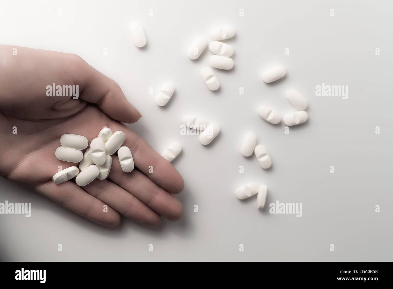 Hand hält viele Dosierungen von chemischen Opioiden medizinischen Pillen und einen Stapel von pharmazeutischen Medikamenten auf sauberen weißen Hintergrund mit Copyspace Stockfoto