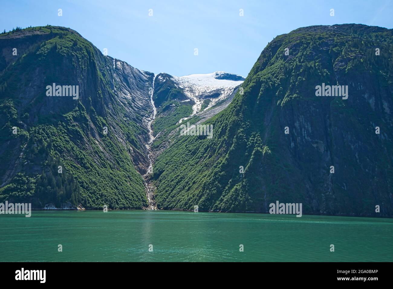 Der schmelzende Schnee bildet einen kleinen Bach, der in den grünen See mündet. Die Fjorde Alaskas, einzigartige Naturlandschaften. Alaska, USA. Juni 2019. Stockfoto