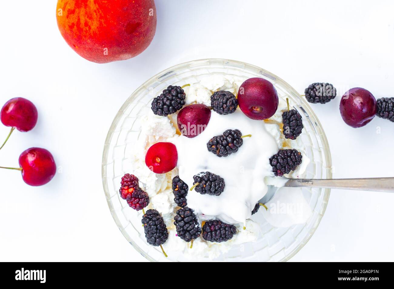 Sommerliche Küche. Eine Schüssel mit Quark und reifen saftigen Kirschen und Maulbeeren, Kokosnusscreme. Ein gesundes, leckeres Dessert. Stockfoto