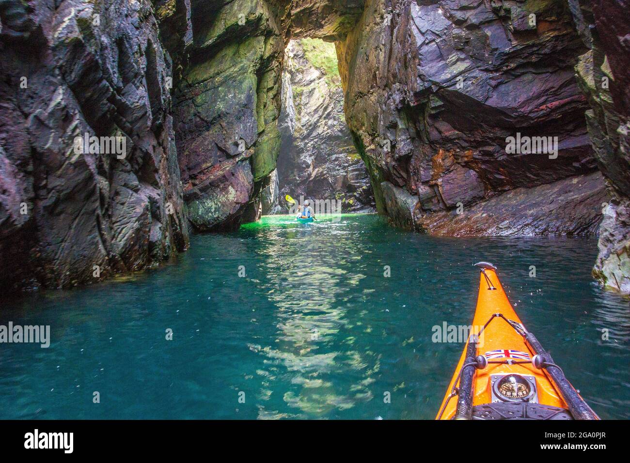 Erkunden Sie Meereshöhlen, während Sie vor der Küste von Anglesey, Nordwales, Großbritannien, Kajakfahren Stockfoto