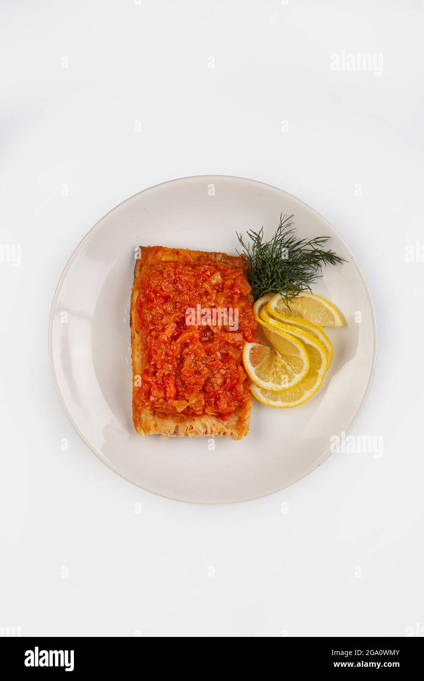 Gerösteter Fisch und Zitrone auf einem Teller auf einem isolierten Studiohintergrund Stockfoto