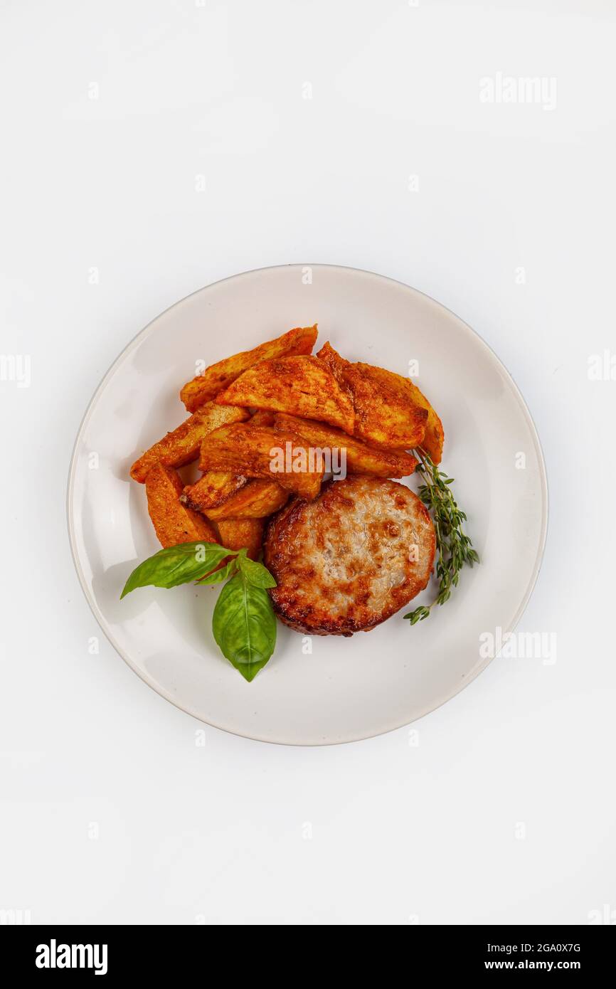 Kotelet, Kartoffeln und Grün auf einem Teller auf isoliertem Studiohintergrund Stockfoto