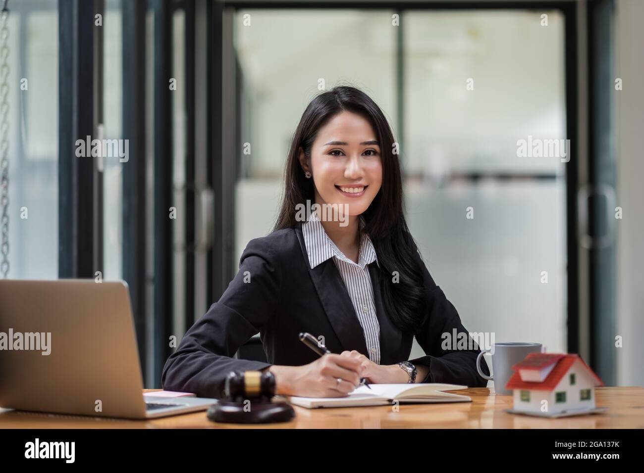 Porträt einer Geschäftsfrau und von Anwälten, die im Büro Vertragsdokumente mit Messingskala auf einem Holzschreibtisch diskutieren. Recht, Rechtsdienste, Beratung, Justiz und Stockfoto