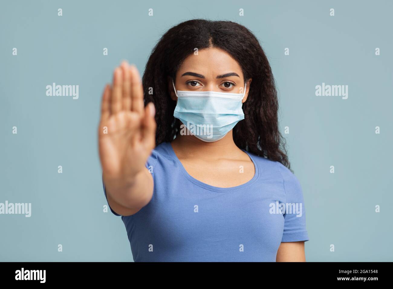 Bekämpfung des Coronavirus während einer Pandemie. afroamerikanische junge Frau in Schutzmaske mit Stop-Geste Stockfoto