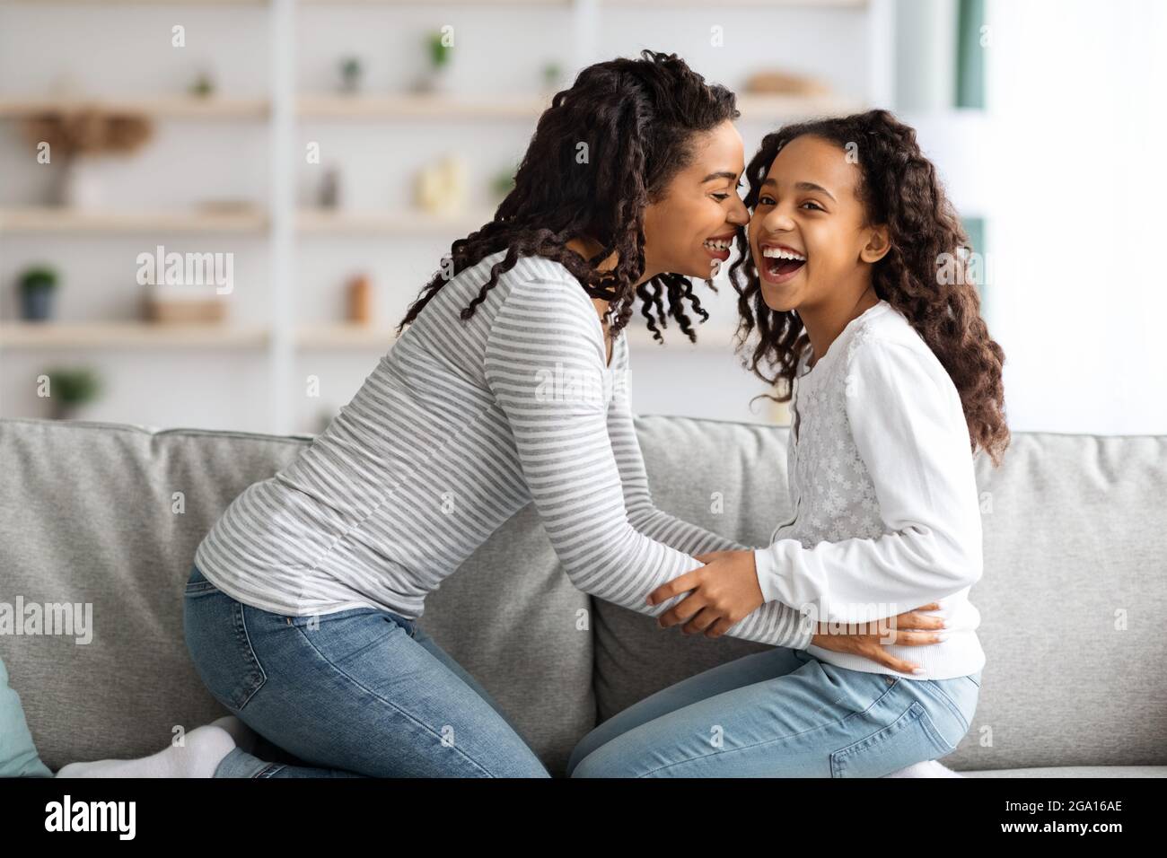 Glückliche afroamerikanische Mutter kitzelt ihr lachendes Kind Stockfoto