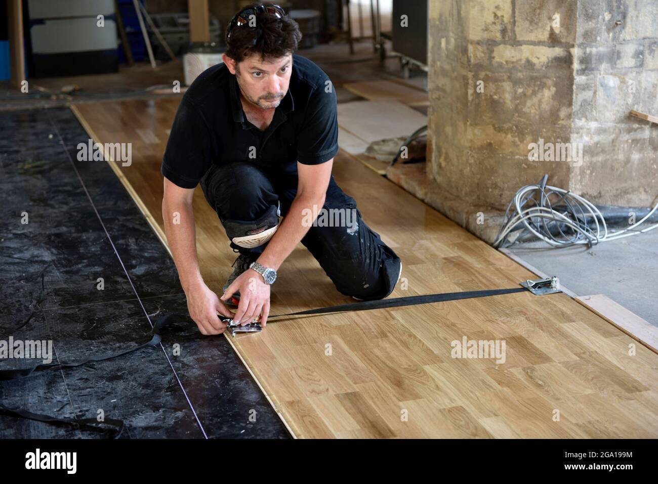 Werker setzt die Druckklemme auf neu installierten Laminat-Holz-Feder- und Nut-Böden Stockfoto