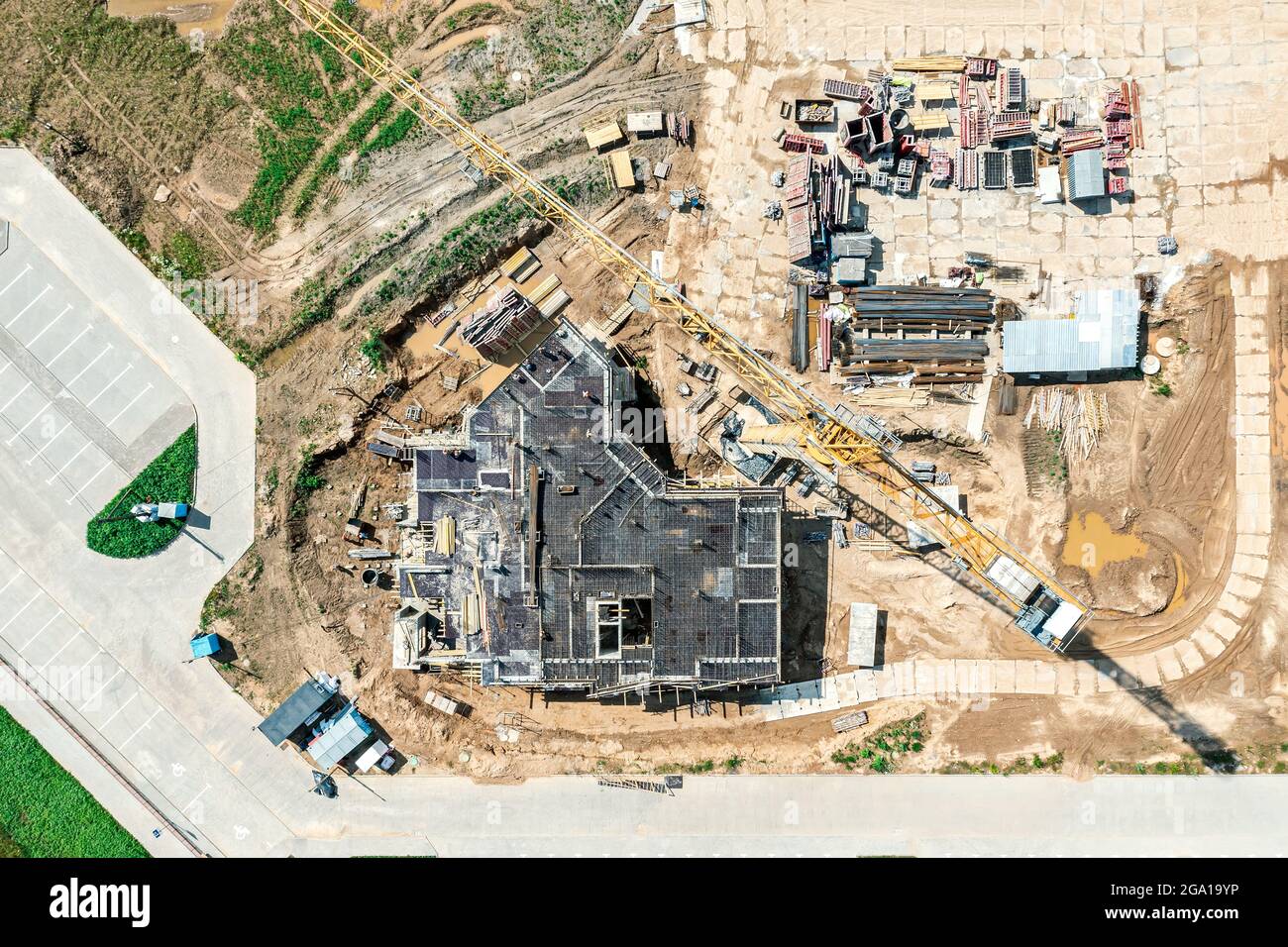 Baustelle des Hochhauses. Bodenplatte im Bau. Funktionstüchtiger gelber Kran. Luftaufnahme von oben. Stockfoto