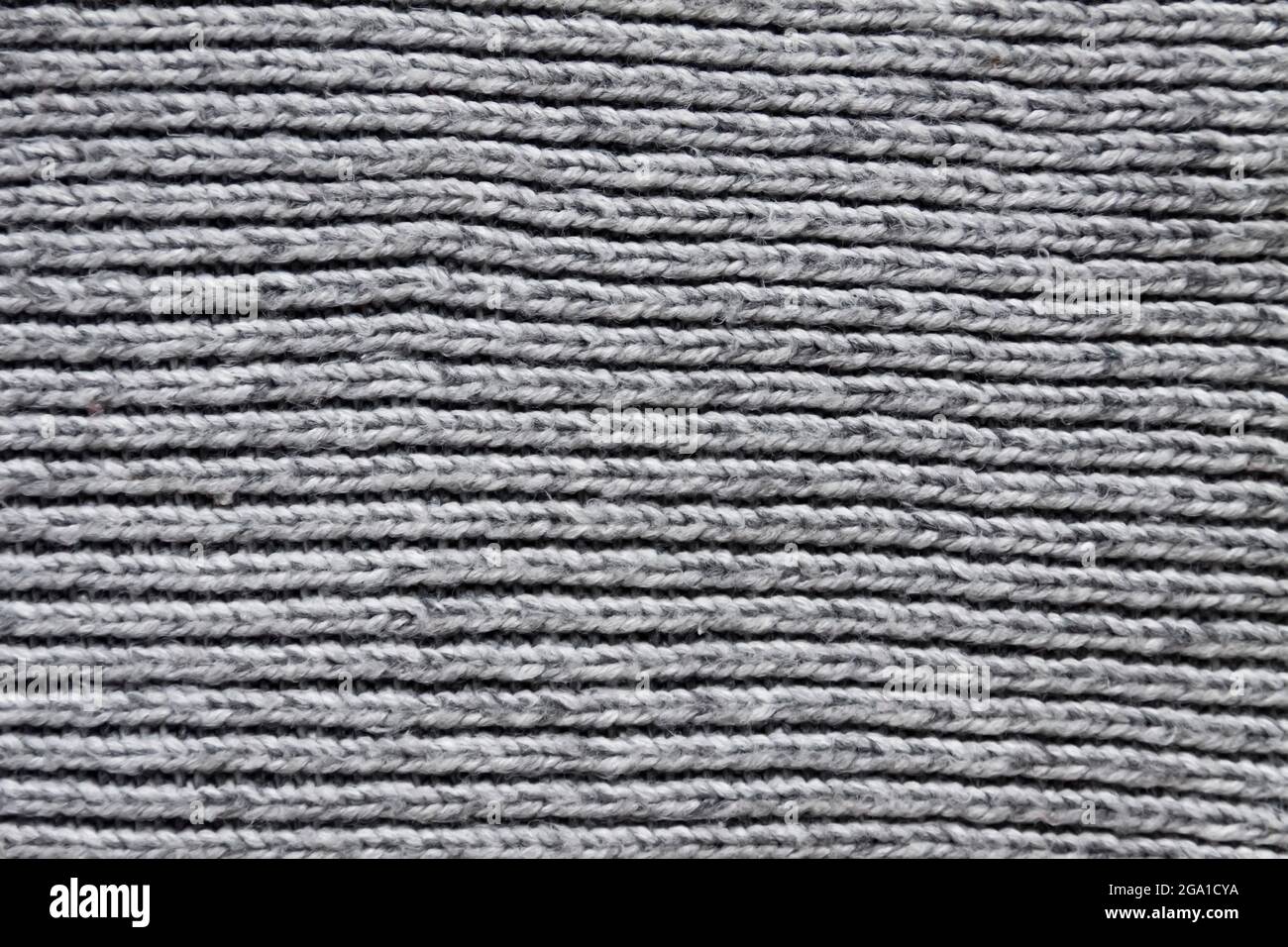 Wolle gestrickte Oberfläche aus grauem Textil Nahaufnahme. Natürlicher textiler Hintergrund. Schweres Strickmuster. Stockfoto