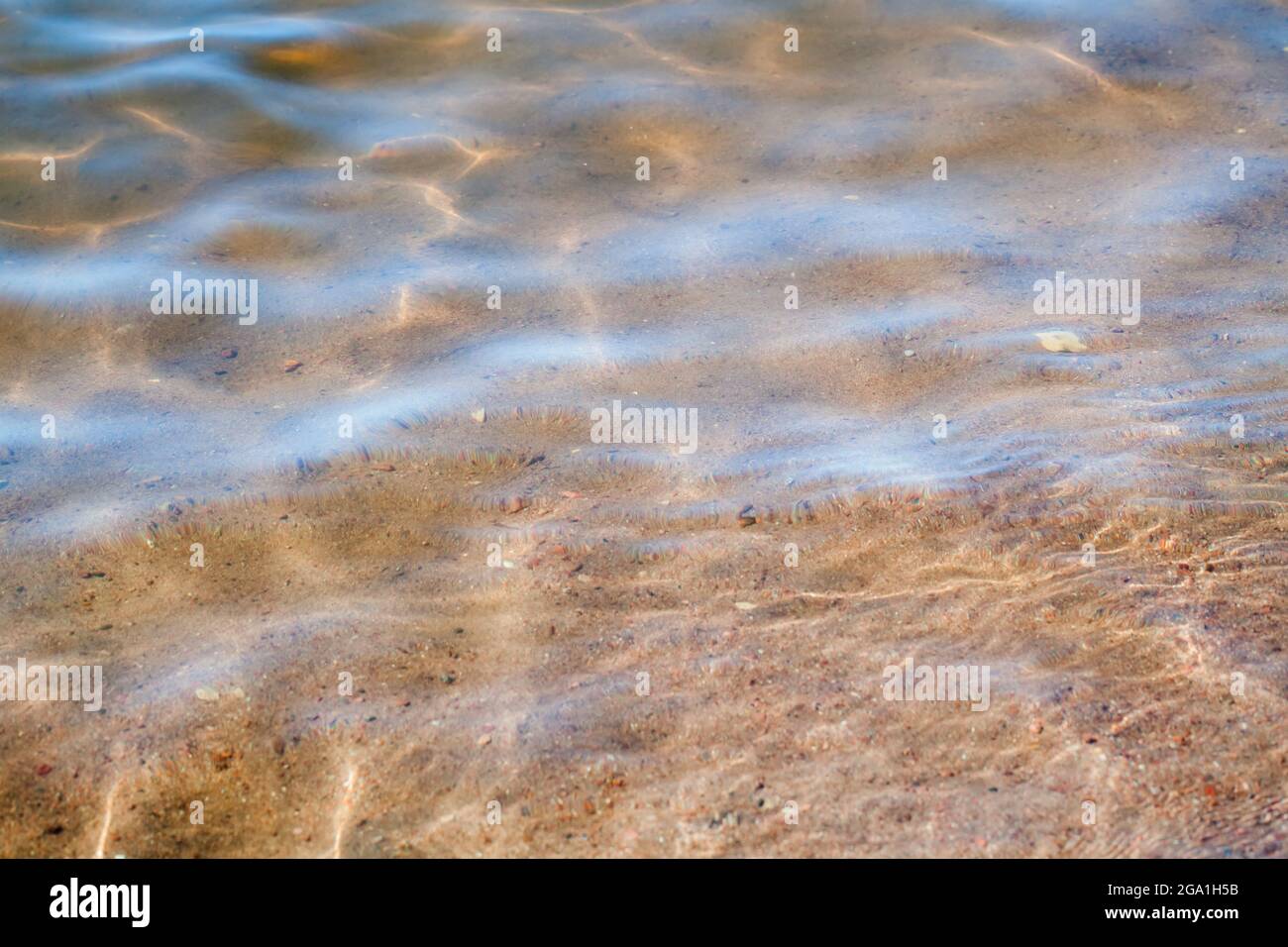 Der sandige Meeresboden liegt unter seichtem Wasser mit Wellenbrechern Stockfoto