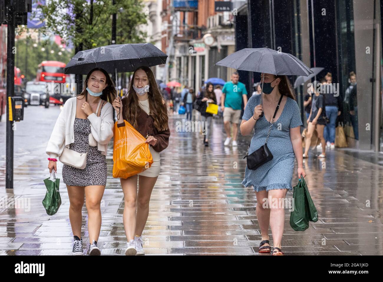 London, Großbritannien. Juli 28 2021: Heavy Rain Showers, Central London, England, UK das Bild zeigt junge Mädchen, die sich unter ihrem Regenschirm vor dem Regen entlang der Oxford Street schützen, während schwere Regenschauer über das Zentrum Londons und den Süden Englands ziehen. Kredit: Clickpics/Alamy Live Nachrichten Stockfoto