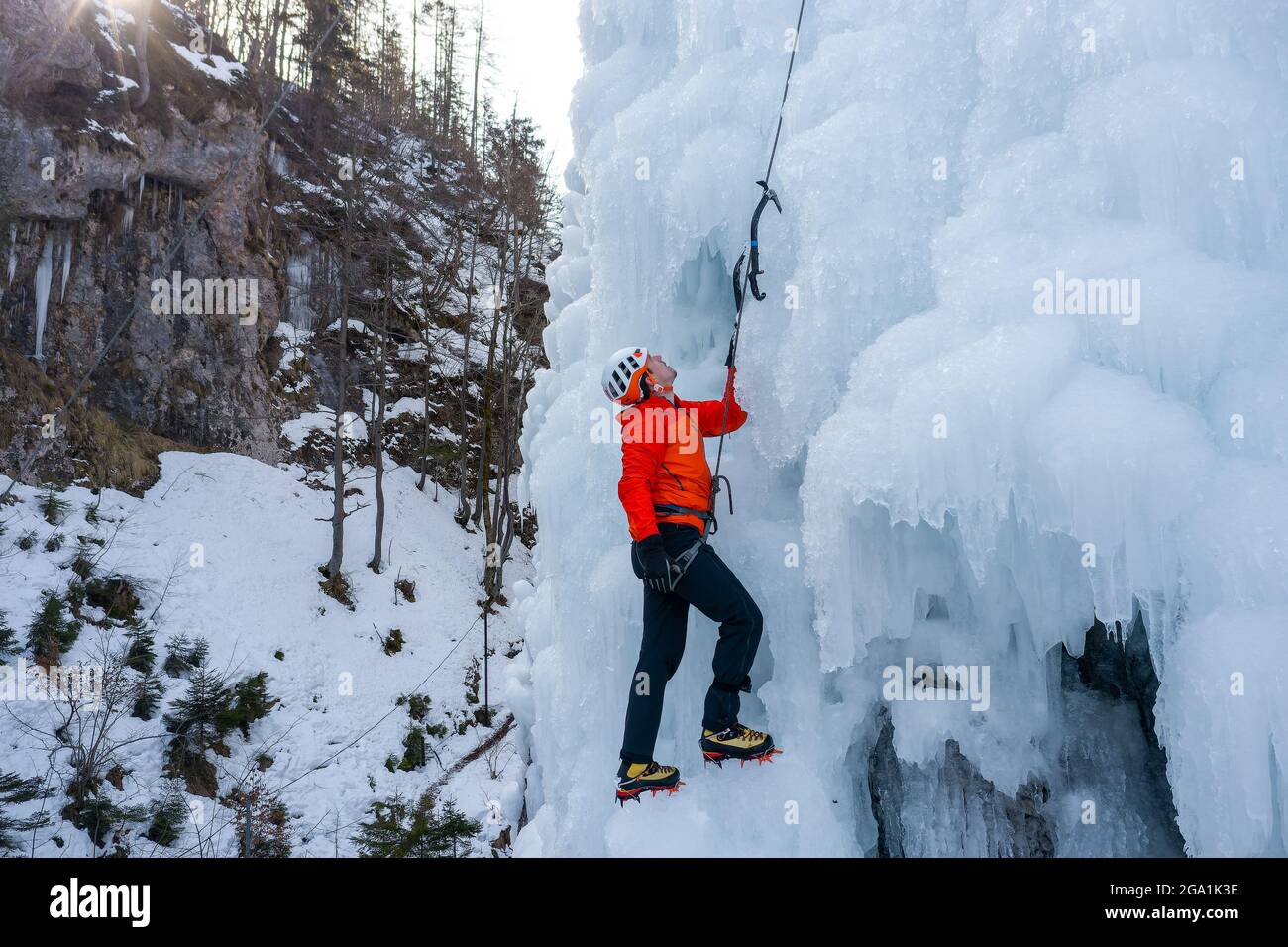 Luftaufnahme eines gefrorenen Wasserfalls und Felsen, bei dem Kletterer seine eisbedeckte Oberfläche mit Eispickeln und Steigeisen aufsteigen Stockfoto