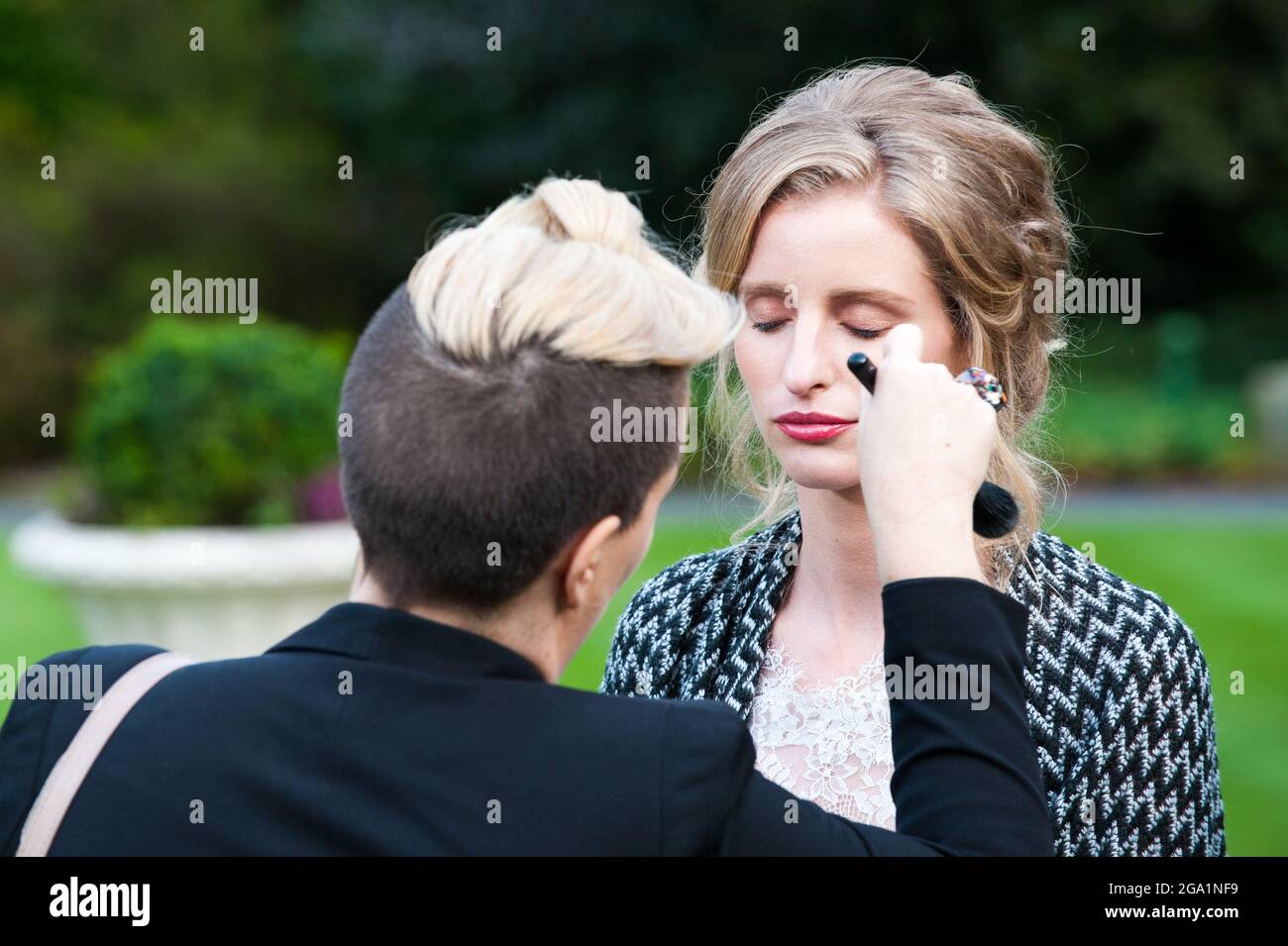 Schöne blonde Mädchen im Brautkleid mit Make-up-Künstler Stockfoto