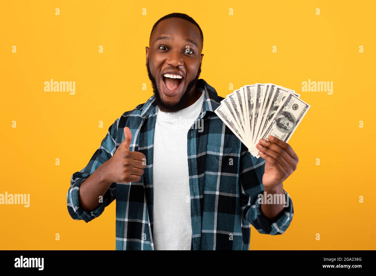 Happy Rich Black Guy Hält Geld Gestikulieren Daumen-Up, Gelber Hintergrund Stockfoto