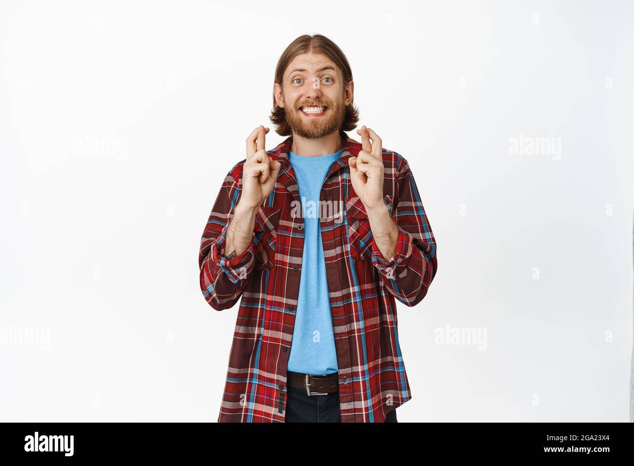 Große Hoffnungen. Aufgeregt blonde Kerl lächelnd und sehnlich Hoffnung, Daumen drücken und Wunsch, Vorwegnahme großer Nachrichten, Hoffnung auf Sieg, gegen stehen Stockfoto
