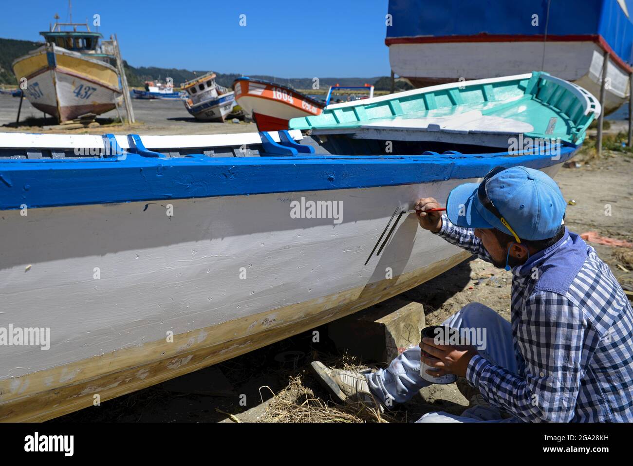 Fischer malt Namen auf seinem Boot Stockfoto