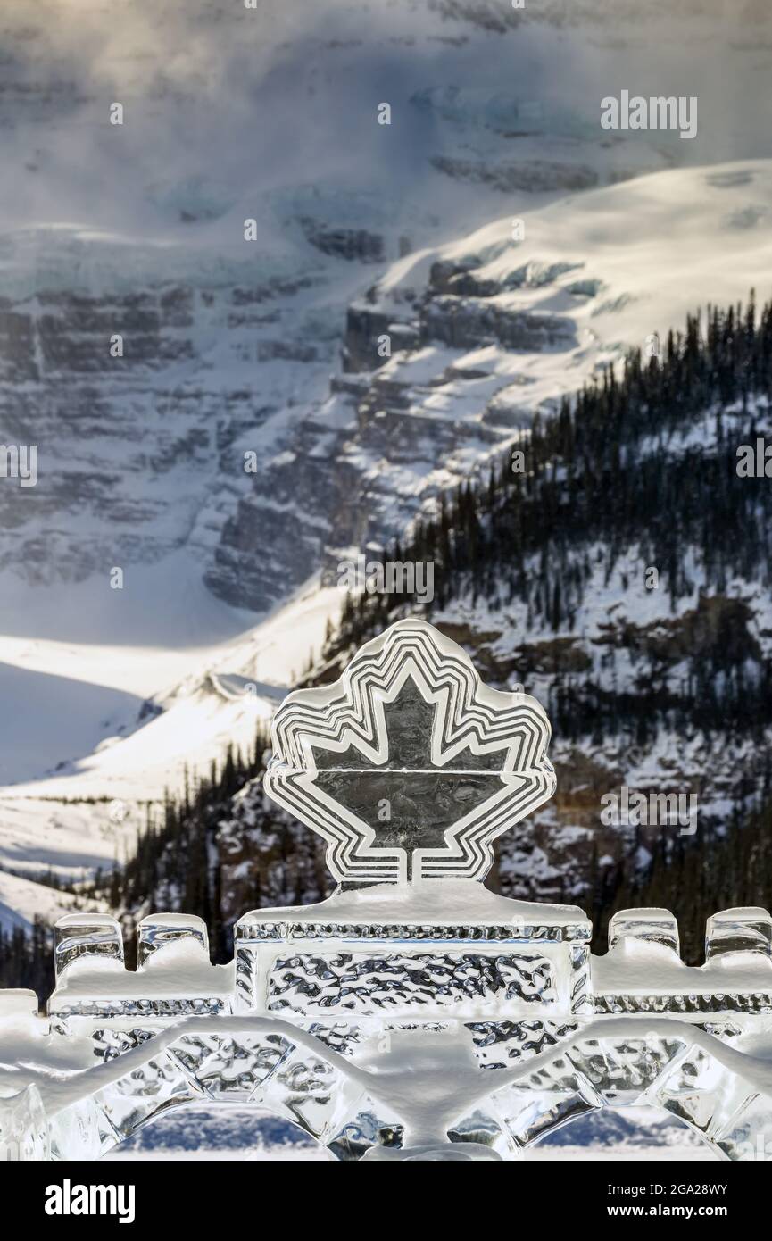 Canadian Maple Leaf Ice Sculpture mit einem Hintergrund eines schneebedeckten Berges im Banff National Park; Lake Louise, Alberta, Kanada Stockfoto
