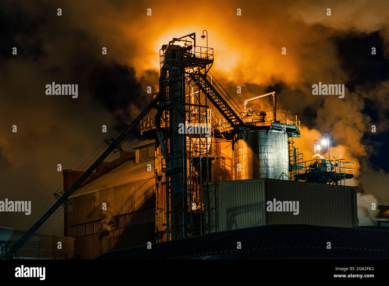 Verarbeitungsanlage mit Emissionen, die nachts mit orangefarbenem Licht leuchten; Nebraska, Vereinigte Staaten von Amerika Stockfoto