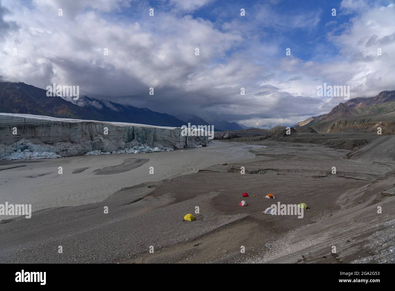 Eine Gruppe von Wanderern schickte ein Basislager mit bunten Zelten vor dem Donjek-Gletscher im Kluane-Nationalpark mit dramatischen Wolkenformationen in der... Stockfoto