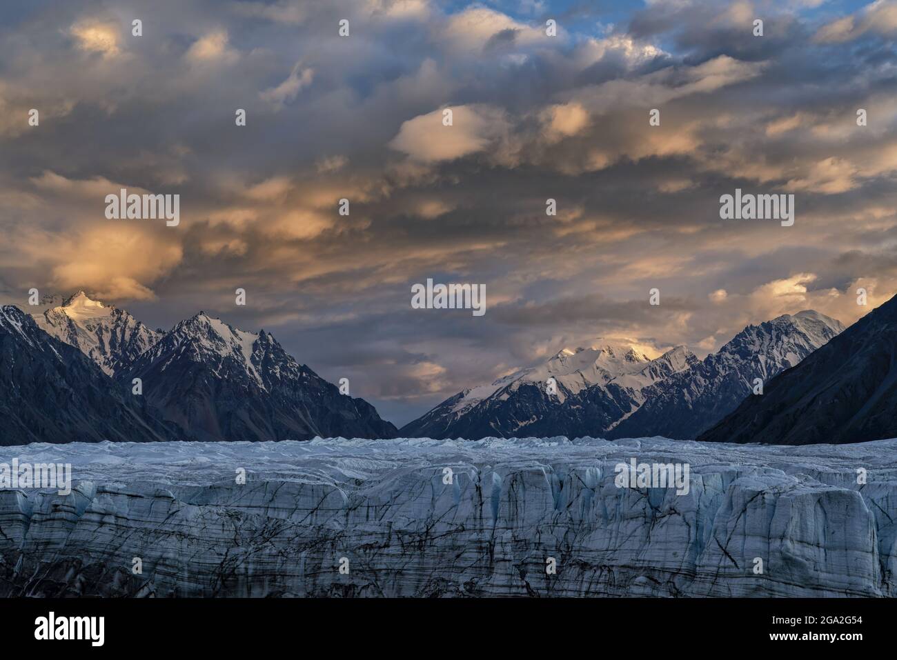 Der riesige Donjek-Gletscher im Kluane National Park mit dem Sonnenuntergang, der die Wolken über den schneebedeckten Berggipfeln erleuchtet, was ein atemberaubendes Bild ... Stockfoto