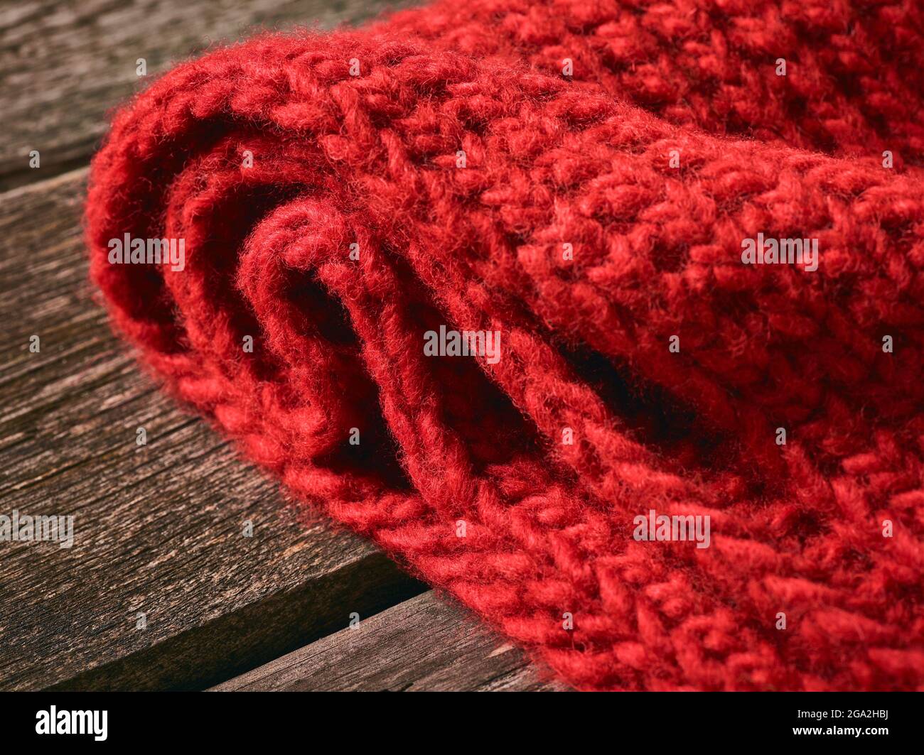 Nahaufnahme eines roten Strickkleides, das auf einem Holztisch liegt; Studio Stockfoto