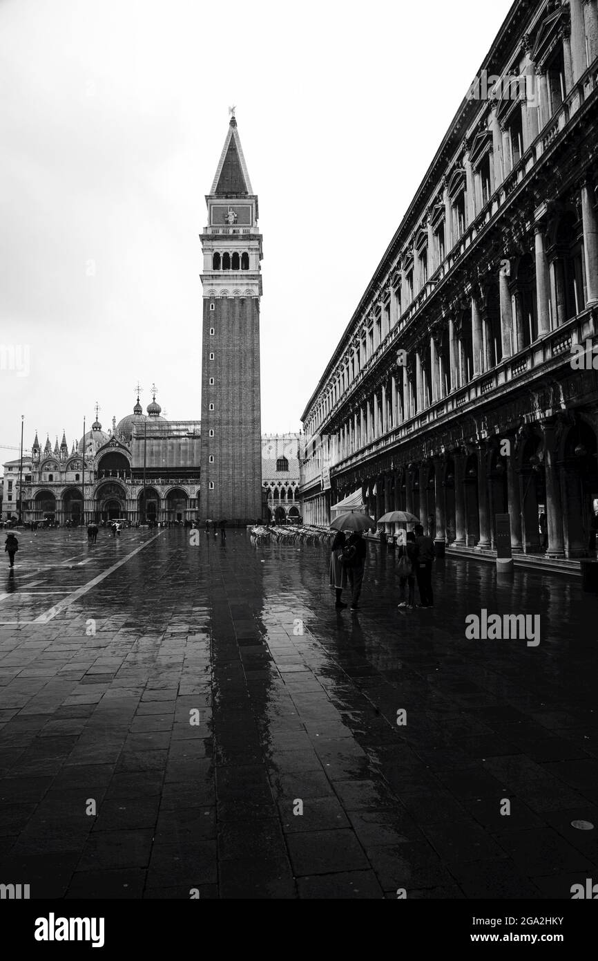 Der ikonische Markusturm und die Markusbasilika auf dem Markusplatz mit Touristen an einem regnerischen Tag; Venedig, Venedig, Italien Stockfoto